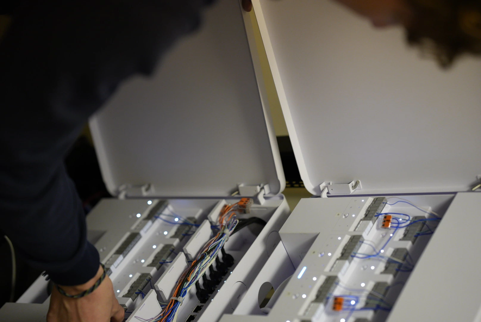 Elektriker i säkerhetsväst arbetar med kablar i kontorstak från stege.