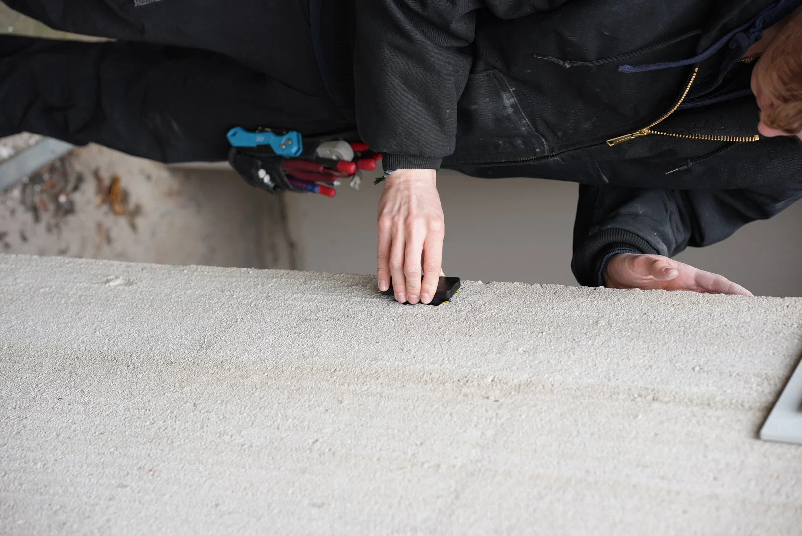 Lasermätare på stativ mäter avstånd i lagerlokal med anteckningsblock bredvid.