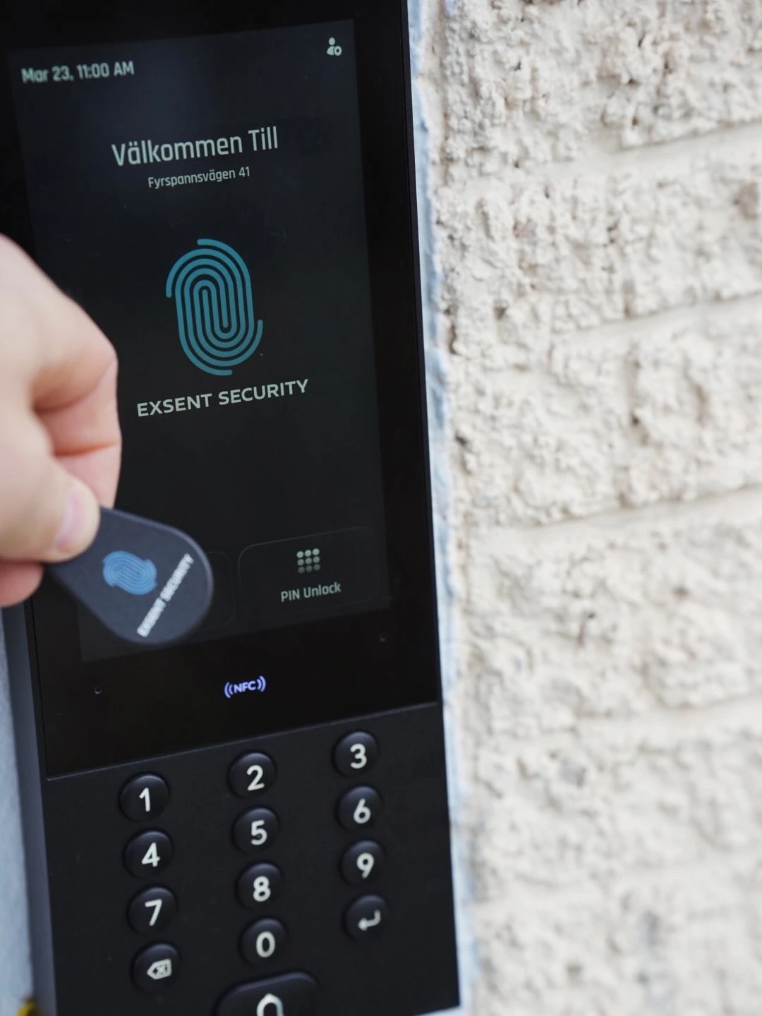 Modern kontaktlös säkerhetspanel monterad vid kontorsentré med Exsent Security skylt.